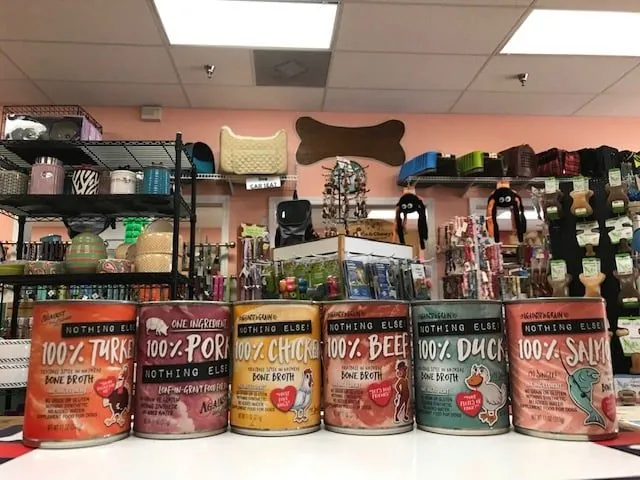 A row of single-ingredient canned pet foods on the counter at Paradise Poochie