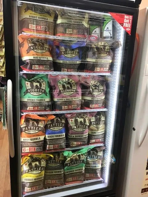 Freezer case of raw frozen pet food nuggets and patties at Paradise Poochie